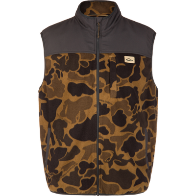 Camp Fleece Vest with camo pattern, dark gray yoke, high collar, chest logo patch; designed for warmth, comfort, and water resistance with practical pockets for hunting or outdoor use.