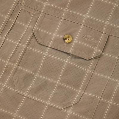 Close-up of a tan, grid-patterned Lifestyle Wingshooter Hunter Creek shirt featuring a chest pocket with a single button and an embroidered logo on the pocket flap.