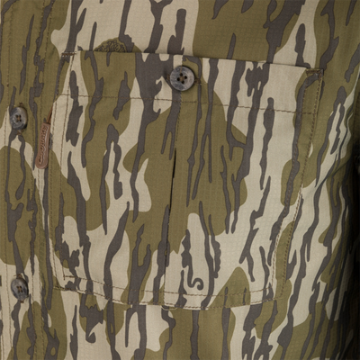 Youth Long-Sleeved 8-Shot Flyweight Shirt with tiger-stripe camo, buttoned pocket flap, top-stitching, and fabric tag, highlighting durable, moisture-wicking polyester and hidden zippers.