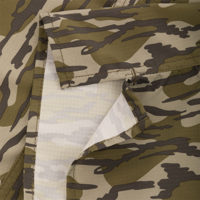 Close-up of the Youth Long-Sleeved Flyweight Shirt's camo fabric, highlighting stitched edges and a folded pocket with lighter interior, showcasing its technical and stylish design.