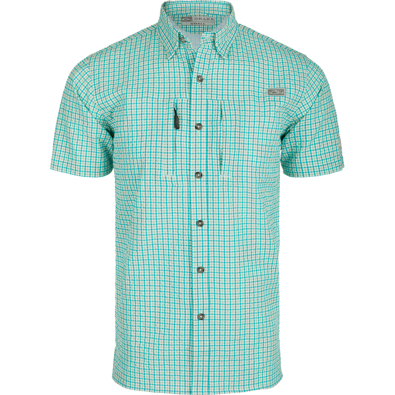 A Classic Seersucker Grid Check Shirt with a hidden button-down collar, zippered chest pocket, and Magnattach™ closure. Made from 76% Polyester and 24% Nylon, it offers UPF30 sun protection and moisture-wicking properties. Vented cape back and split tail hem provide ventilation and versatility. Perfect for hunting, fishing, or casual wear.