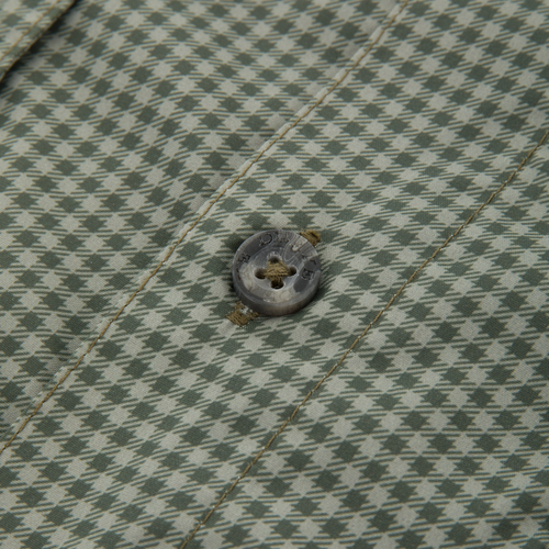 Close-up of the Frat Gingham Check Button-Down Long Sleeve Shirt, highlighting green-and-off-white houndstooth fabric with a four-hole button and visible stitching.