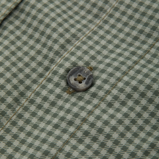 Close-up of the Frat Gingham Check Button-Down Long Sleeve Shirt, highlighting green-and-off-white houndstooth fabric with a four-hole button and visible stitching.