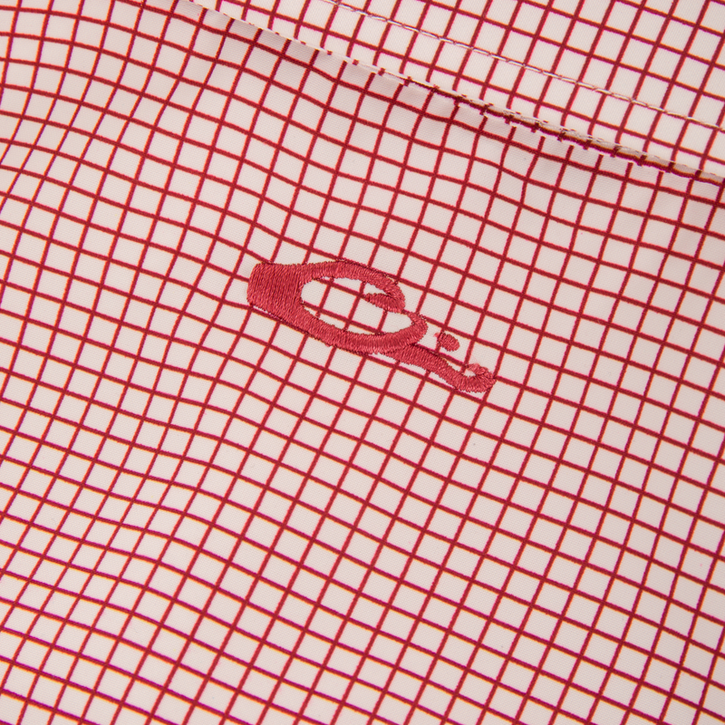 Wingshooters Trey Grid Check Short Sleeve Shirt showcasing a red grid pattern, embroidered logo, stitched seam, and performance features like moisture-wicking and UPF30 sun protection.