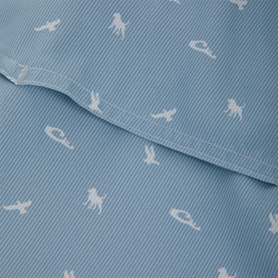Close-up of the Cinco Ranch Western Short Sleeve Shirt showcasing light-blue striped fabric with white animal silhouettes and a visible seam, highlighting its intricate design.