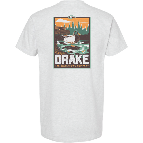 Mallard Blind Scene T-Shirt featuring a drake in a marsh with duck blind silhouette, evergreens, and orange sky. Bold DRAKE text highlights the Waterfowl Company's theme.