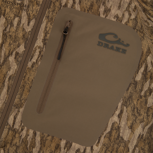 Close-up of Drake's EST Offset 1.0 Half Zip Pullover, highlighting zippered pocket, woodland camo pattern, and Drake logo, emphasizing comfort and functionality features.