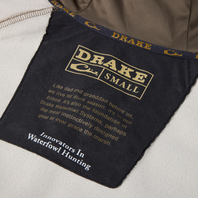 Label inside the MST Offset 2.0 Half Zip Hoodie by Drake Waterfowl, detailing size, heritage blurb, and tagline Innovators In Waterfowl Hunting.