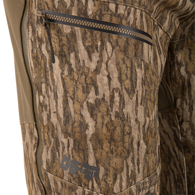 Close-up of the MST CommandXT Softshell Pant showcasing a zip-closed pocket with the COMMANDO logo on camouflage fabric, highlighting durability for demanding hunting activities.