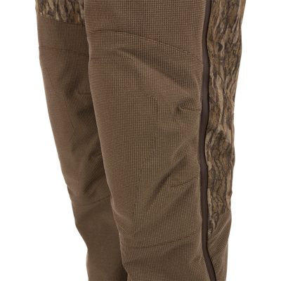 Close-up of the LST CommandXT Bib with Primaloft showing a camo side-panel, brown fabric with grid pattern, and vertical zippered seam for durability and warmth.