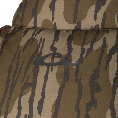 Camouflage-patterned fabric with stitching seam, part of the BMF Drake Down Vest, designed for layering and core warmth in challenging hunting conditions.