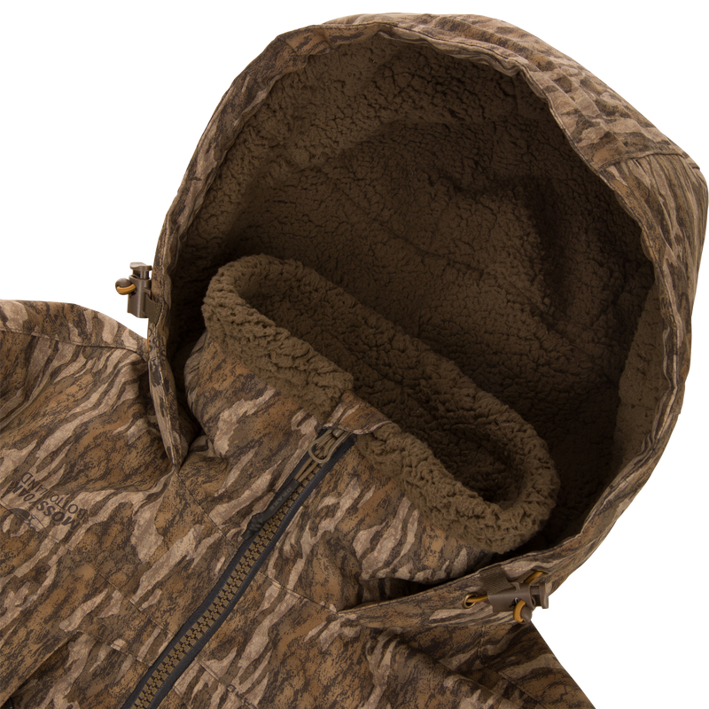 LST BMF Eqwader Half Zip Jacket with Primaloft, featuring camo-pattern, sherpa-lined hood, front zipper, and hood-adjustment toggles, designed for warmth and functionality in outdoor conditions.