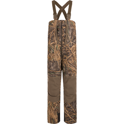 The Waterfowl LST BMF Pit Bib with Primaloft features adjustable straps, reinforced knees, and a brown-green camo pattern. Made from waterproof ripstop polyester for impact protection during outdoor or hunting use.