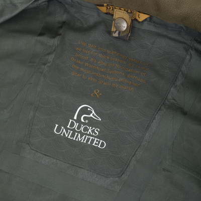 Interior of a Drake X Ducks Unlimited LST BMF 3-in-1 Pit Jacket with Primaloft featuring a logo and a printed quote about the tradition of duck hunting.
