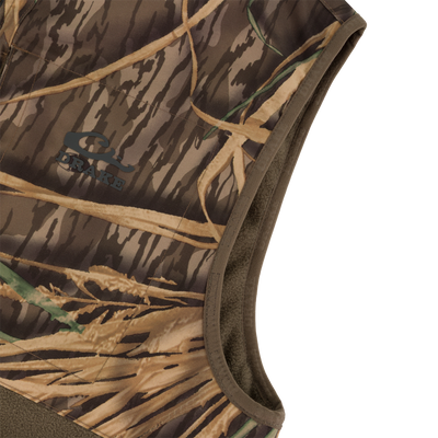 Close-up of the CommandXT Eqwader Vest by Waterfowl: a sleeveless, abrasion-resistant vest with brown/tan camo pattern, brown trim, DRAKE logo on the chest, and durable material.