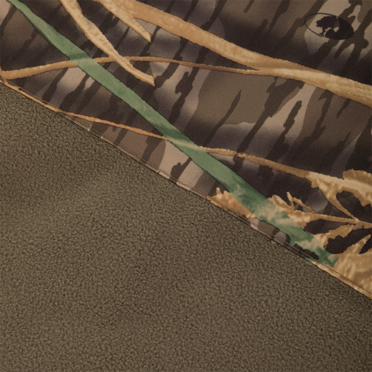 Close-up of camouflage fabric in brown, green, and tan next to solid olive green material, both from the Waterfowl CommandXT Eqwader Vest.