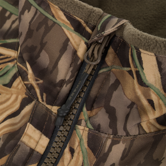 Close-up of the CommandXT Eqwader Vest by Waterfowl, showing its camouflage pattern and abrasion-resistant texture with a partially open zipper.