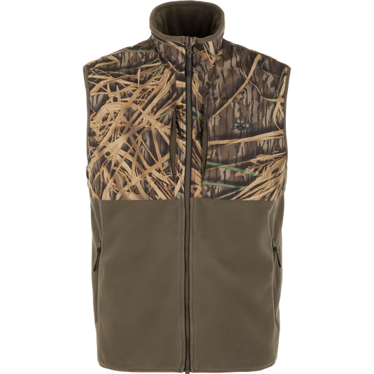 The CommandXT Eqwader Vest by Waterfowl is a sleeveless zip-up hunting vest featuring an olive green fleece bottom and a brown grass and branch camouflage upper, shown on a white background.
