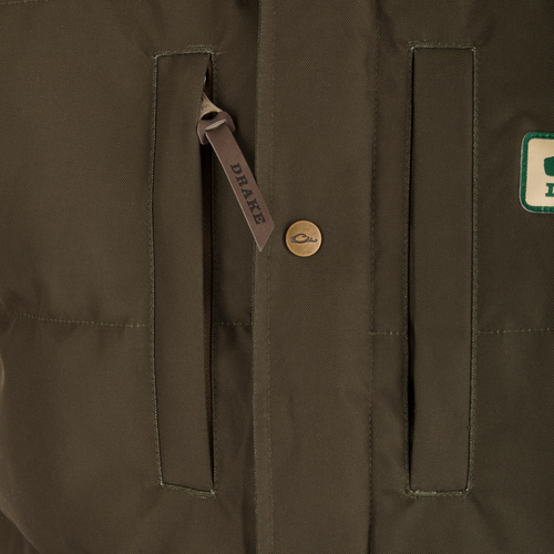 Close-up of Drake's Throwback 80 Featherless Puffer Jacket, featuring vertical welt pockets, embossed brass snap, and leather zip pull tab stamped “DRAKE.”