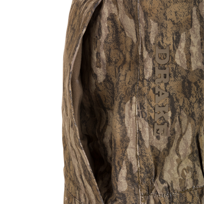Close-up of a DRAKE LST Hardline Insulated Bib, showcasing camo-patterned shell, seam detail, and a pocket for optimal warmth and weather protection.