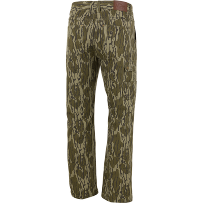 Back view of green and brown camouflage Throwback 80 Field Pant by Waterfowl in heavyweight cotton twill, with multiple pockets, straight legs, and a brown leather patch on the waistband.