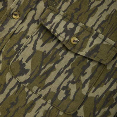 Close-up of the Throwback 80 Button Down Shirt, showcasing its camouflage-patterned fabric, flap pocket, four-hole buttons, and durable triple-stitched seams for hunting apparel.