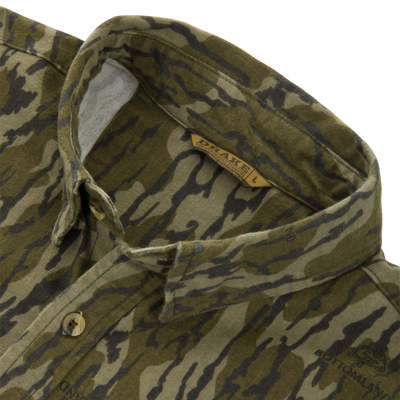 Close-up of Throwback 80 Button Down Shirt's collar, showcasing green-and-brown camouflage pattern, branded button, and durable cotton twill material with reinforced stitching.
