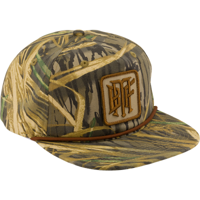 The Drake x Lost Hat BMF Goat Rope Cap by Waterfowl features Mossy Oak Original Shadow Grass camo, a brown rope above the brim, and a square patch with stylized letters.