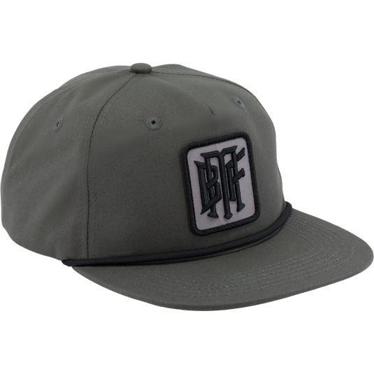 The Drake x Lost Hat BMF Goat Rope Cap by Waterfowl is a gunmetal baseball cap with a flat bill, black and white embroidered patch, and an adjustable snapback for the perfect fit.