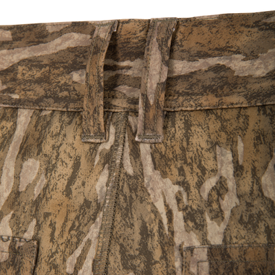 Close-up of the waistband and belt loops on Waterfowl BMF Ultimate Wader Pants in brown and tan camo, showing stitching detail, fabric texture, and a polyester fleece shell.