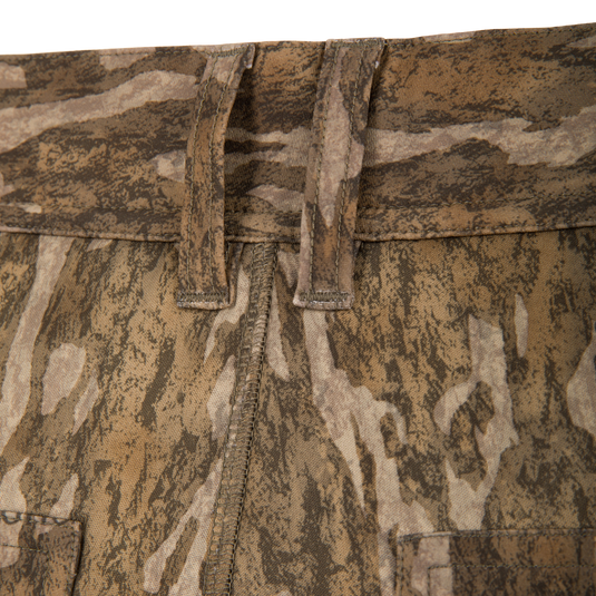 Close-up of the waistband and belt loops on Waterfowl BMF Ultimate Wader Pants in brown and tan camo, showing stitching detail, fabric texture, and a polyester fleece shell.