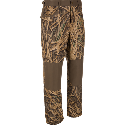 The Waterfowl MST Jean Cut Wader Pant features water-resistant fabric with a brown and tan grass camo pattern, plus solid brown knees and thighs, shown on a white background.