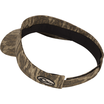 The Drake Logo Visor by Waterfowl features a camouflage pattern, curved bill, velcro back closure, and an embroidered oval Drake logo on the front.