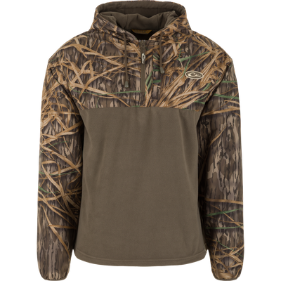 The Waterfowl MST Quarter Zip Refuge Eqwader Jacket with Hood features Mossy Oak Original Shadow Grass camo on the sleeves, hood, and chest, with solid olive green on the lower front and back.