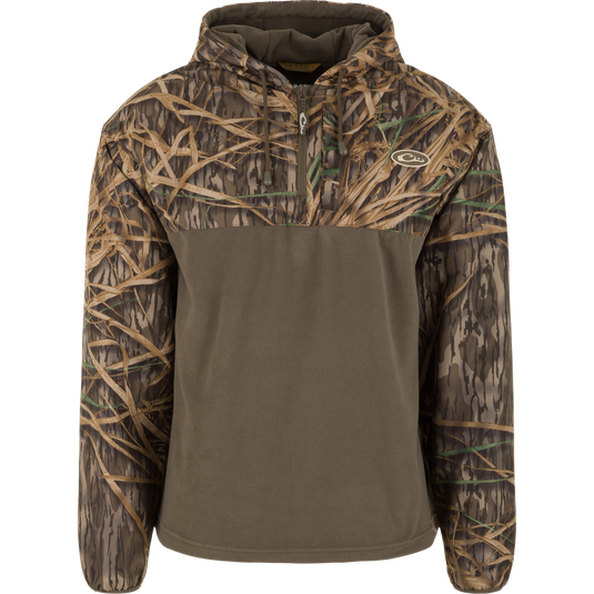 The Waterfowl MST Quarter Zip Refuge Eqwader Jacket with Hood features Mossy Oak Original Shadow Grass camo on the sleeves, hood, and chest, with solid olive green on the lower front and back.