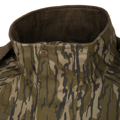 Close-up of an MST Drake Dry Waxed Cotton Wading Jacket in camouflage, featuring a high, dark green corduroy-lined collar and a snap-button closure.