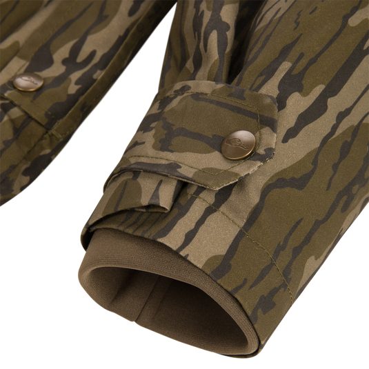 Close-up of the Waterfowl MST Drake Dry Waxed Cotton Wading Jacket, showing sleeves with adjustable snap-button tabs at the wrists and dark green inner cuffs.