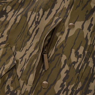 Close-up of an MST Drake Dry Waxed Cotton Wading Jacket in camouflage, featuring a vertical zippered chest pocket and metal snap buttons.