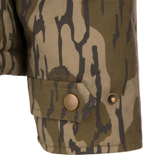 Close-up of a buttoned cuff tab on the sleeve of a LST Insulated Waxed Cotton Jacket in camouflage.