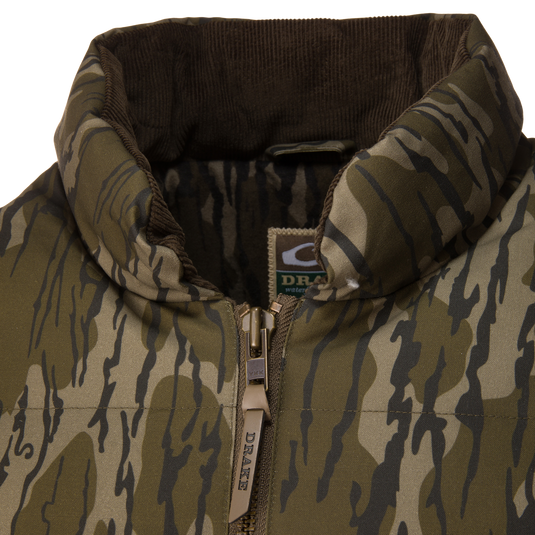 Close-up of a Waterfowl LST Insulated Waxed Cotton Jacket, featuring a camouflage-patterned, featherless design with a brown corduroy collar and a zippered front.