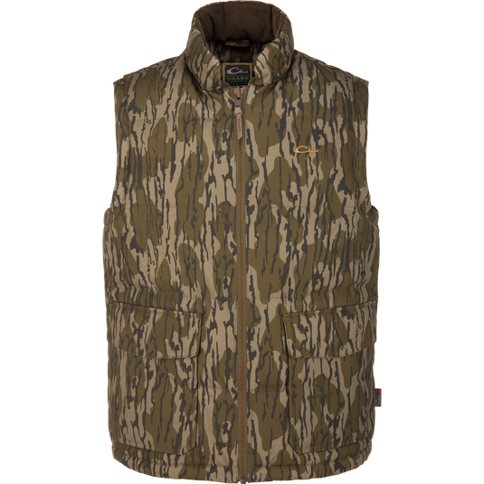 The Waterfowl LST Insulated Waxed Cotton Vest in Mossy Oak Original Bottomland features Thinsulate insulation, a zip-up front, and two large pockets, shown sleeveless against a white background.