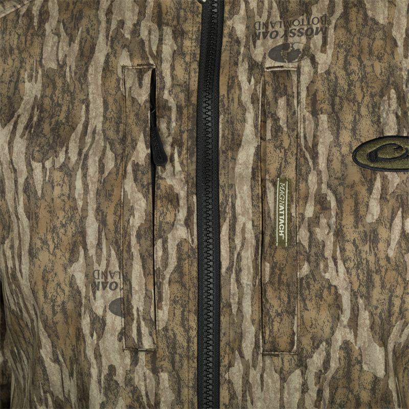 Drake MST Windproof Softshell Jacket in Mossy Oak camo, featuring Magnattach™ chest pockets, heavy-duty zipper, and branded details for hunting enthusiasts.