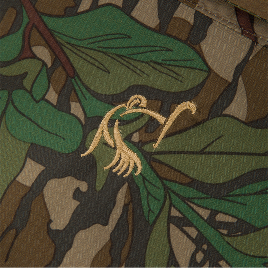 Close-up of Men's Camo Wingshooter Trey Shirt, highlighting its camouflage fabric and technical features like hidden pockets and vented design.