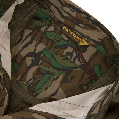 Men's Camo Wingshooter Trey Shirt, featuring a close-up of its camouflage fabric, highlighting the label and logo, emphasizing high-performance, moisture-wicking, and sun-protection features.