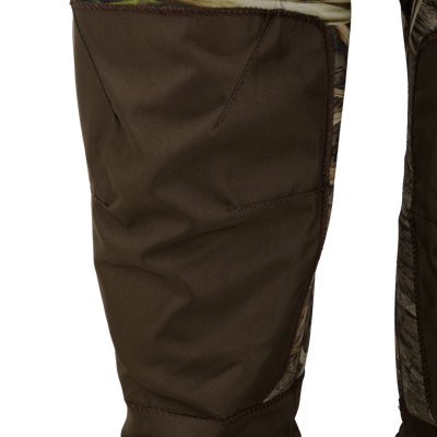 Close-up of Spoonie Youth Mud-Sucker Neoprene Waders featuring reinforced brown knee pads over a camouflage print.