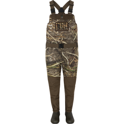 Spoonie Youth Mud-Sucker Neoprene Waders in Mossy Oak Shadow Grass Habitat camouflage with dark brown reinforced knees, suspender straps, and integrated insulated hunting boots.