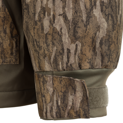 Close-up of a camouflage Spoonie Waterproof Fleece Lined Quarter Zip Jacket sleeve with an olive green ribbed cuff and a hook-and-loop fastener.