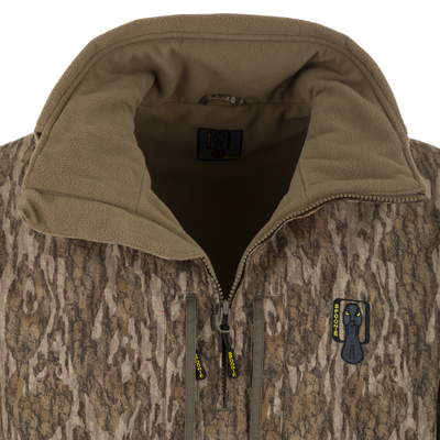 Spoonie Waterproof Fleece Lined Quarter Zip Jacket in a camouflage tree-bark pattern with a breathable polyester shell and a black duck logo patch on the chest.
