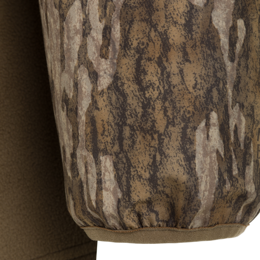 Close-up of a Spoonie Eqwader Quarter Zip sleeve featuring a brown and tan tree bark camouflage pattern with an elasticized cuff.