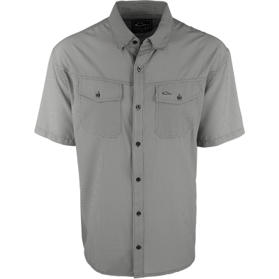 A close-up of the Traveler's Check Shirt S/S, a black and white shirt with collar and button details. Made with a lightweight, breathable poly/spandex fabric for ultimate comfort and freedom of movement. Ideal for the man on the go, whether on vacation or running errands. Moisture-wicking and wrinkle-resistant. 2 chest pockets with button flaps.